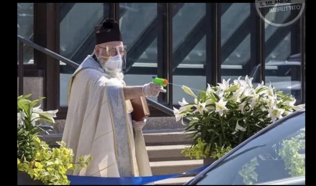 Un prete durante la sua messa benedice i fedeli con una pistola d'acqua